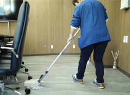 会議室の床を掃除用具で清掃する北進のスタッフ